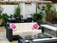 Outdoor room with sofas, dining table, gas effect fire, built-in seating, mirror, steel panel water feature, lighting, raised beds.