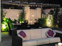 Outdoor room at night with sofas, dining table and lighting