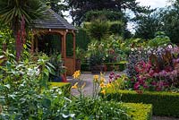 The Exotic Garden at Abbeywood. Formal box edged beds contain plants including daylilies, Cleome,  Dahlia, Nicotiana and Canna with Cordyline australis, Musa, Paulownia and Trachycarpus palms behind.