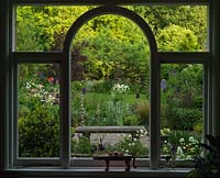 The view from the kitchen window frames an old apple tree, seen through borders of Iris, Aquilegia, Allium and Valerian,