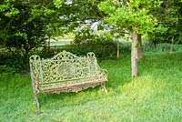 Old, lichened cast iron bench in the field. King John's Nursery, Etchingham, East Sussex, UK