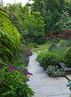 A natural flagstone path leads along a mixed flower border through to the lawn.