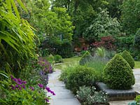 A natural flagstone path leads along a mixed border and topiary through to the lawn.