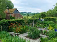 Kitchen garden with cutting garden of sweet peas, foxtail lilies, alstroemeria and delphinium. Raspberries and vegetables. Views past cottage to River Test valley in distance.