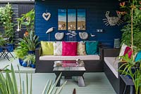 A covered seating area with seaside inspired decorations, sofa and table.