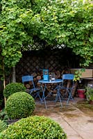 A secluded seating area under a pergola supporting a large grape vine.