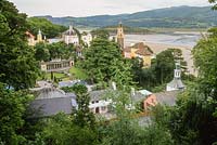 Portmeirion. View of village, designed by Sir Clough William-Ellis, on hillside overlooking bay, on peninsula in Snowdonia, North Wales.