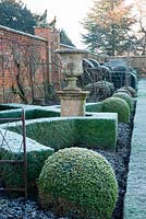 Formal box knot garden with urn in border in walled garden at Helmingham Hall, Suffolk