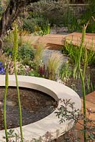 Royal Bank of Canada Garden. Pools of water surrounded by decking with Foxtail lilies and Rosa glauca syn rubrifolia in the foreground and Stipa tenuissima, Leptospermum scoparium 'Red Damask' and Erigonron karvinskianiks growing in the gravel.