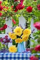 Cut flower arrangement with roses on garden table in summer. Rosa 'Crimson Glory' - climbing rose