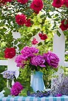 Cut flower arrangement with jug of Peony and Ladys Mantle on garden table in summer.