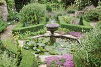 Small octagonal pond with fountain, nymphaea and formal box hedging, King's Cliffe, Northants