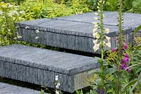 Steps made from hand-cut slate stacked together, flanked by foxgloves and Euphorbia pasteurii. The Brewin Dolphin Garden. RHS Chelsea Flower Show, 2015