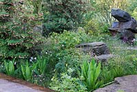 The Laurent-Perrier Chatsworth Garden. Border with boulders, Enkianthus campanulatus, Rosa rubiginosa and Dipsacus fullonum