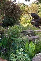 Naturalistc recreation of Trout stream and Paxton's rockery. Rosa canina, Enkianthus campanulatus meadow planting - The Laurent-Perrier Chatsworth Garden. RHS Chelsea Flower Show, 2015