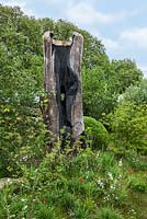 The Laurent-Perrier Chatsworth Garden. Burnt tree trunk sculpture, teasels, English oak, tulips and ragged robin.