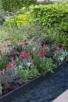 Raised flowerbeds next to water feature with decorative slate. The Telegraph Garden, inspired by De Stijl Movement and reflecting strong rectilinear geometry with planting blocks contributing colour and textural relief. RHS Chelsea Flower Show, 2015