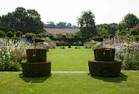 Yew topiary castellated with colourful flower borders at Felley Priory, Nottinghamshire