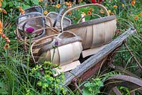 A Trugmaker's Garden. Old trolley with trug baskets surrounded by cottage garden flowers.