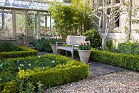 Terrace with decorative wooden bench in a formal garden with clipped Box hedging 