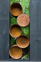 Rusted tin cans set in upright black wooden sleepers. - The Great Chelsea Garden Challenge Garden.  RHS Chelsea Flower Show, 2015