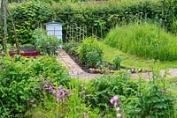 Garden wildflower area with reclaimed pamment pathway leading to traditional beehive