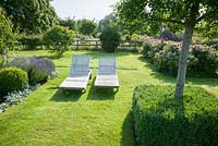 A pair of wooden sun loungers on the lawn