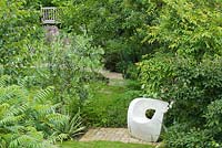 A view over the garden with its winding paths and sculptured seat. Plants include: Sumack, Betual utilus, Olea Europaea, Magnolia, Thalictrum and Euphorbia. Seat by Solid Soul Furniture Designs.