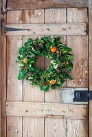Christmas wreath with dried fruit and cinnamon bundles mounted on a door.