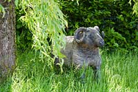 Wooden sculpture of a sheep beneath a willow tree.