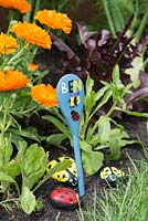 Painted wooden spoon to indicate a child's garden, with pebbles painted as ladybirds.
