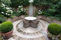 Walpole Gardens: London. View onto circular tile and brick sunken patio with Carpinus betulus, Hydrangea arborescens 'Annabelle', Salvia 'Caradonna', Erigeron karvinskiansus, Heuchera 'Rave On', Buxus sempervivens