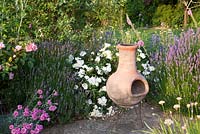 Terracotta chiminea on garden patio with Rosa, Dianthus and Lavender. Bradness Gallery, East Sussex. Owners: Artists Michael Cruickshank and Emma Burnett