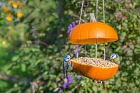 A pair of blue tits eating seed from the Pumpkin Bird Feeder