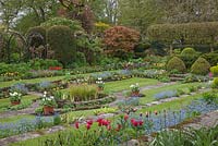 Chenies Manor Gardens, Buckinghamshire, showing the 'Sunken Garden' in Spring. Planting includes Tulipa, Myosotis, Hosta, Euphorbia, Primula, Carex elata 'Aurea'