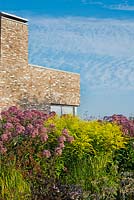 Contemporary house with late summer borders: Solidago 'Golden Musa', Eupatorium 'Riesenschirm', Foeniculum vulgare. Piet Oudolf garden in Hummelo.