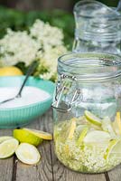 Making an Elderflower drink. Sliced Lemon, Lime, Sugar and Elderberry flowers added to glass jar