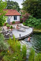 Couple relaxing by and in a natural swimming pond. 