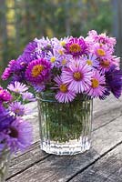 Mixed aster flowers displayed in jam jars
