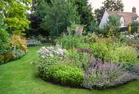 View of cottage garden in summer with island beds. Erigeron, nepeta, hemerocallis and salvias. July