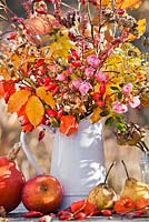 Autumn leaves and perennials in a jug: rosehips, asters, roses, Persicaria, beech, Physalis, Verbena bonariensis