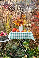 Autumn leaves and perennials in a jug: rosehips, asters, roses, Persicaria, beech, Physalis, Verbena bonariensis. Harvest on a table in fall.