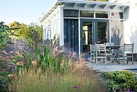 Contemporary house and garden. relaxing area. Hornbeam hedges, Pennisetum alopecuroides 'Cassian', Buddleja, Lythrum virgatum. Van de Voorde garden. Design: Tom de Witte