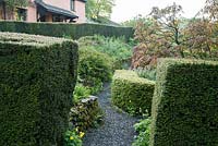The 'best' garden at the front of the house is the most formal area of the garden, with clipped hedges of yew and box framing a mix of herbaceous plants and shrubs including Aesculus pavia 'Rosea Nana'. Windy Hall, Windermere, Cumbria, UK