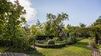 Formal potager with rows of vegetables, formal hedges, trellis, Rosa 'Apple Blossom, paved paths and central container with Foeniculum vulgare 'Atropurpureum' - June, Le Jardin de Marguerite, France