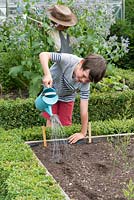 Oscar Isaac, 8, waters newly planted seeds in his vegetable patch.