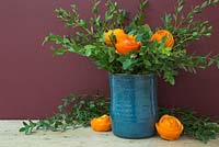 Flower heads crafted from orange peel, accompanied with Eucalyptus in a blue vase