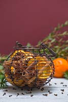 A scented wire basket containing Star anise, dried Citrus fruit and Cinnamon sticks