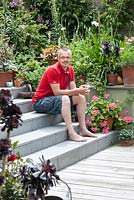 Martin Woods in is back garden sitting on step with potted plants