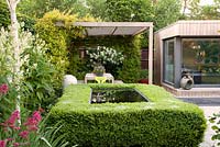 Clipped box hedge around Infinity pool with white Astilbe, Red Valerian, Silver Birch trees with covered seated area for entertaining and summer house beyond. Birdbath by artist Sarah Walton